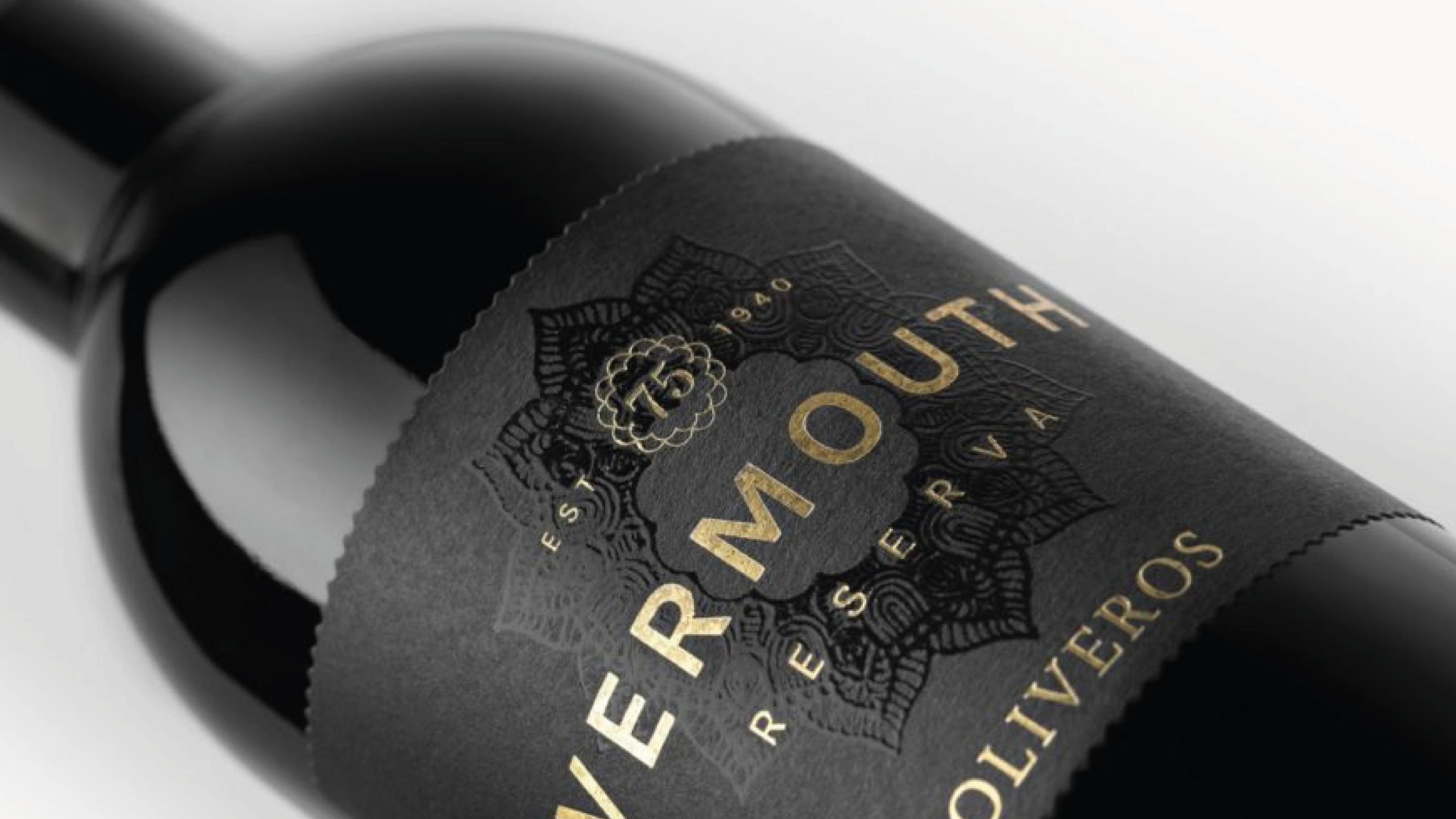 botella de vino negro mate con etiqueta adhesiva en negro y stamping dorado